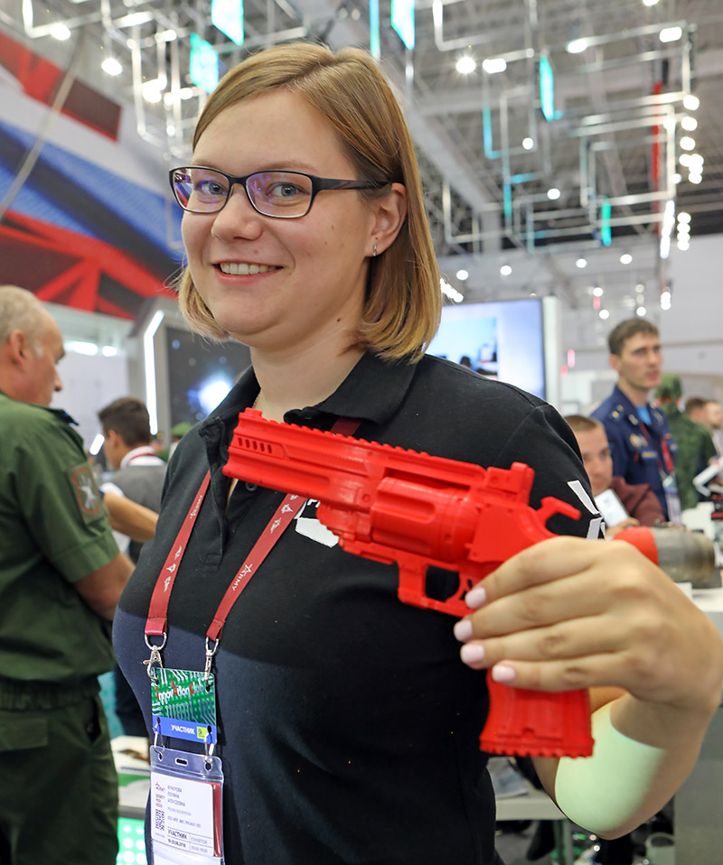 Полина Кучерова из компании PICASO 3D показывает распечатанный на принтере красный револьвер.