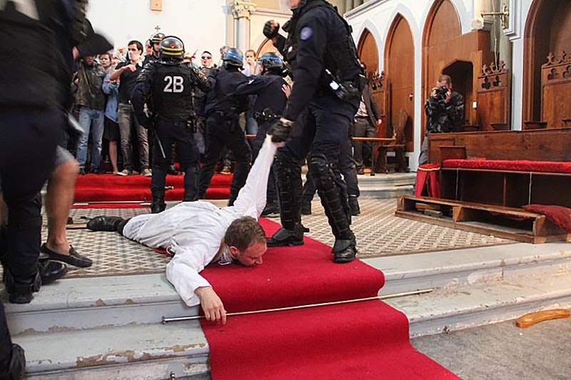 Полиция выволакивает священника из церкви Святой Риты в Париже.
