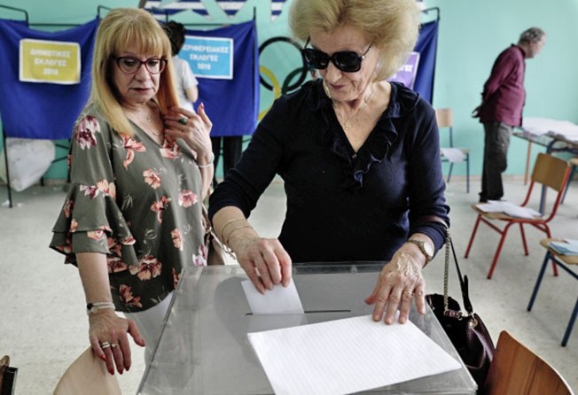 Избиратели во время голосования на выборах в Европейский парламент (ЕП) на одном из избирательных участков в Афинах.