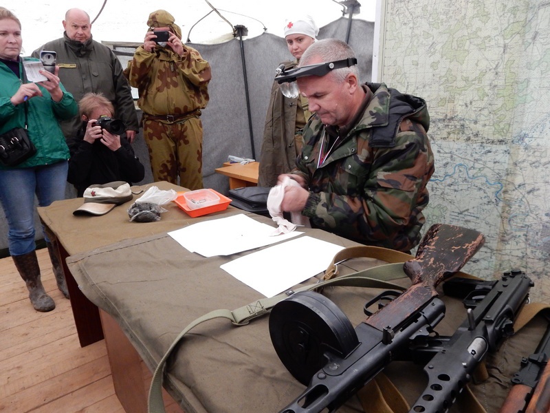 Процесс извлечения записки из медальона погибшего советского воина под Ржевом, в палатке лагеря поисковиков.
