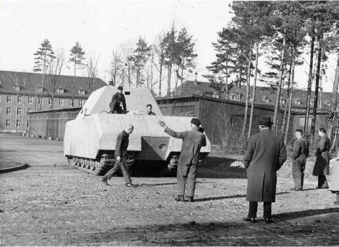 Немецкий опытный сверхтяжёлый танк «Маус» во время ходовых испытаний на полигоне в городе Бёблинген. Спиной к зрителю в шляпе стоит конструктор танка Фердинанд Порше.