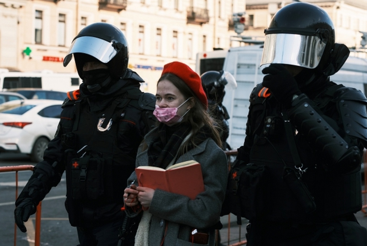 Сотрудники полиции сопровождают девушку, задержанную на несанкционированной акции в Санкт-Петербурге против военной операции на Украине.