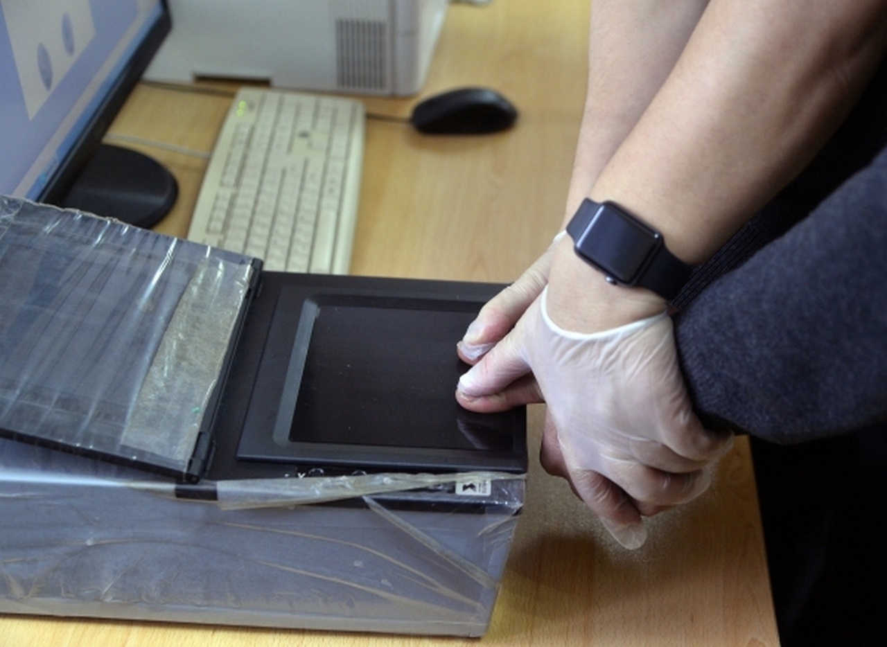 Сотрудник полиции сканирует отпечатки пальцев у мужчины во время оперативно-профилактических мероприятий «Нелегальный мигрант».